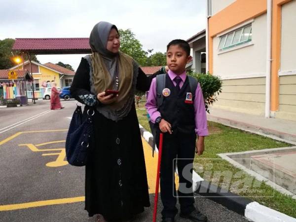 Norlela menemani Irfan yang bertongkat ke sekolah.