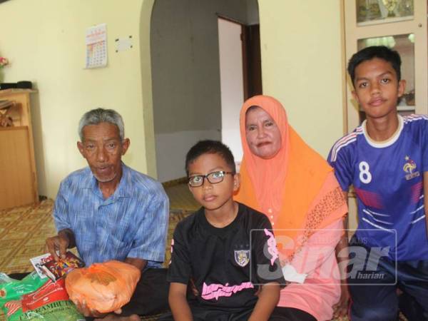 Syukri (tengah) bersama bapanya, Johan dan ibunya Samsiah di rumah mereka di Kampung Tanjung Piai, Serkat.