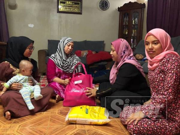 Irmalini (dua dari kanan) turut menyerahkan sumbangan kepada Nour Shafinar ketika menziarahi balu Allahyarham Mejar Zahir di kediaman ibu bapanya di Taman Perpaduan di sini.