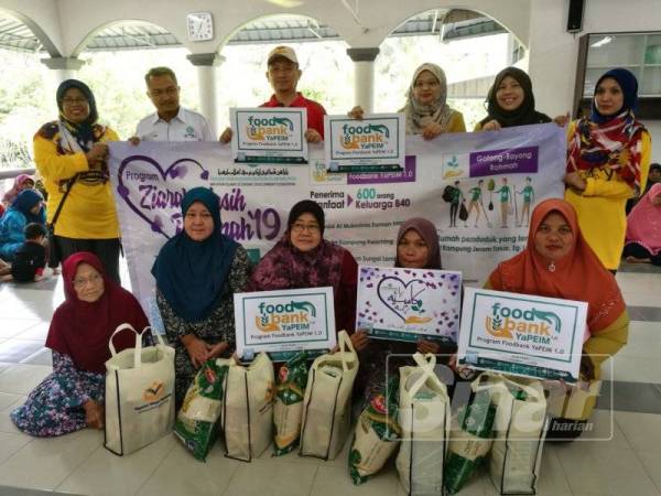 Parihah (berdiri, tiga dari kanan) merakamkan gambar bersama sebahagian penerima sumbangan pada Program Foodbank 1.0 sempena Program Ziarah Kasih Rahmah di Masjid Kampung Panching, dekat sini hari ini.