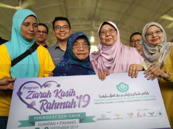 Fuziah (dua dari kanan) menyampaikan simbolik sumbangan membaik pulih rumah asnaf kepada salah seorang penerima sempena program tersebut.