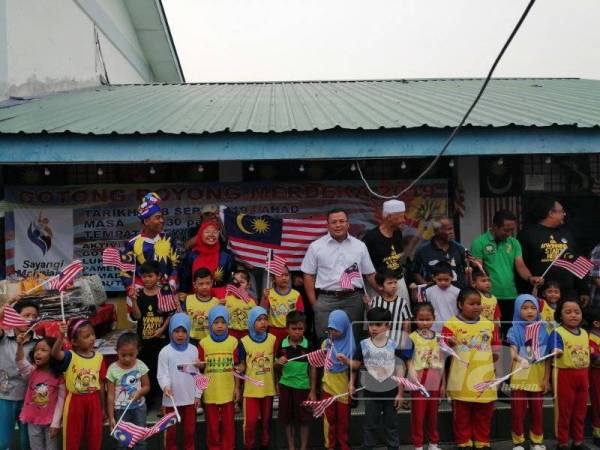 Amirudin (tengah) bersama anak-anak dari Sungai Tua menyanyikan lagu Negaraku disusuli Jalur Gemilang pada program gotong-royong merdeka 2019 di Dewan MPKK Sungai Tua hari ini.