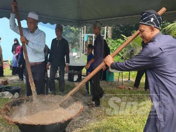 Wan Hassan (kiri) mengacau bubur asyura di Pusat Jagaan Anak Yatim Rohaniah.