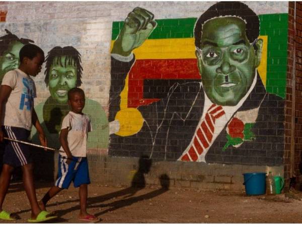 Dua kanak-kanak lelaki melintasi lukisan mural bekas Presiden Zimbabwe, Robert Mugabe di Harare. 