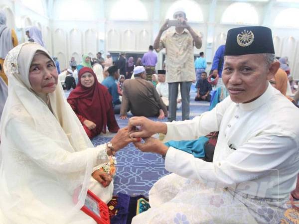 Muajam (kanan) menyarungkan cincin kepada Siti Habsah dalam majlis Nikah Jamaie Syarie di sini.