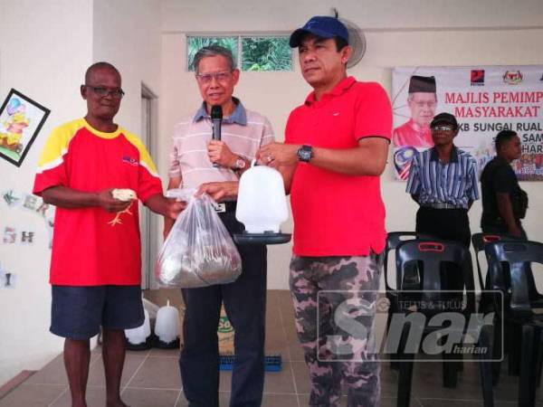 Mustapa menyerahkan baka ayam organik, makanan serta bekas air kepada salah seorang penerima di sini semalam.