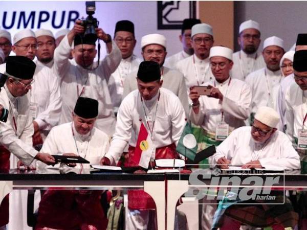 Presiden UMNO, Datuk Seri Dr Ahmad Zahid Hamidi dan Presiden Pas, Datuk Seri Abdul Hadi Awang menandatangani Piagam Muafakat Nasional pada Himpunan Penyatuan Ummah di Pusat Dagangan Dunia Putra (PWTC) Sabtu lalu. - Foto SHARIFUDIN ABDUL RAHIM
