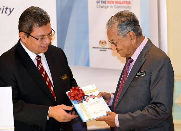 Dr Mahathir (kanan) menerima buku Kerangka Dasar Luar Malaysia Baharu daripada Menteri Luar, Datuk Saifuddin Abdullah selepas melancarkan kerangka dasar luar tersebut di Putrajaya di sini hari ini. - Foto Bernama