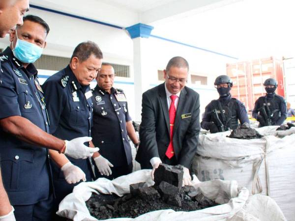 Abdul Hamid (tiga dari kiri) melihat sebahagian daripada 60 tan arang batu yang dicampur kokain.