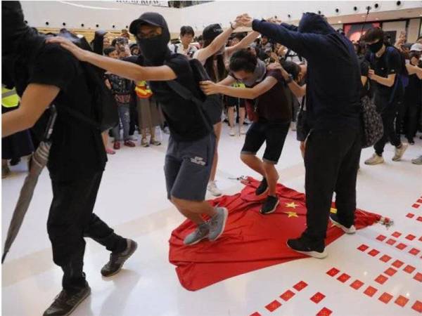 Penunjuk perasaan prodemokrasi Hong Kong memijak bendera China semasa bantahan di bandar Sha Tin semalam. - Foto Agensi