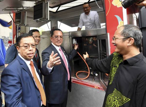 Mohammad menunjukkan alat pengesan asap yang dipasang pada food truck selepas merasmikan garis panduan keselamatan kebakaran food truck di ibu pejabat Jabatan Bomba dan Penyelamat Malaysia (JBPM) hari ini. - Foto Bernama
