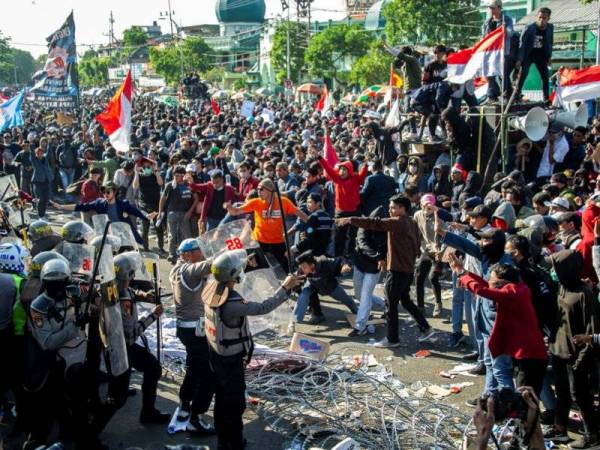 Kumpulan pelajar Indonesia berkonfrontasi dengan polis semasa tunjuk perasaan di hadapan bangunan Parlimen di Surabaya hari ini.