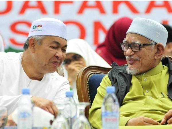 Ahmad Zahid (kiri) berkata sesuatu yang mencuit hati Abdul Hadi (kanan) sehingga kedua-duanya kelihatan tersenyum di pentas ceramah Muafakat Nasional UMNO-Pas di Dewan 2020, malam tadi. -Foto Pas Perlis