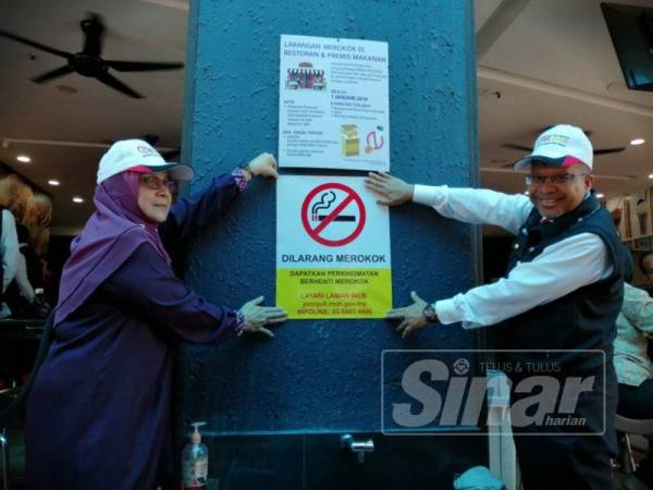 Dr Siti Mariah dan Dr Khalid menampal notis larangan merokok dalam premis makanan pada sesi walkabout di Seksyen 7, Shah Alam.