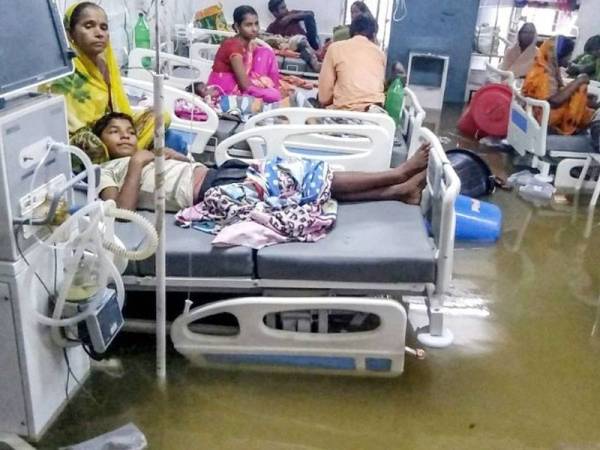 Gambar menunjukkan pesakit terbaring di atas katil hospital dalam air hujan kotor di Kolej Perubatan dan Hospital Nalanda di Patna.- Foto AFP