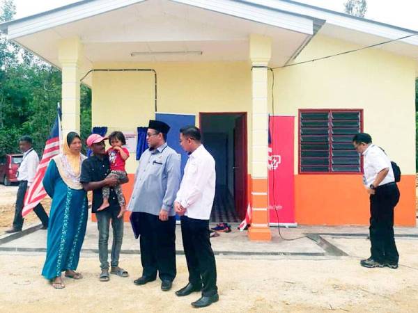 Rozlin (dua dari kiri) bersama Suhami (dua dari kanan) dan Farizan (kanan) di hadapan rumah baharu diterimanya melalui projek Baiti Jannati TNB.