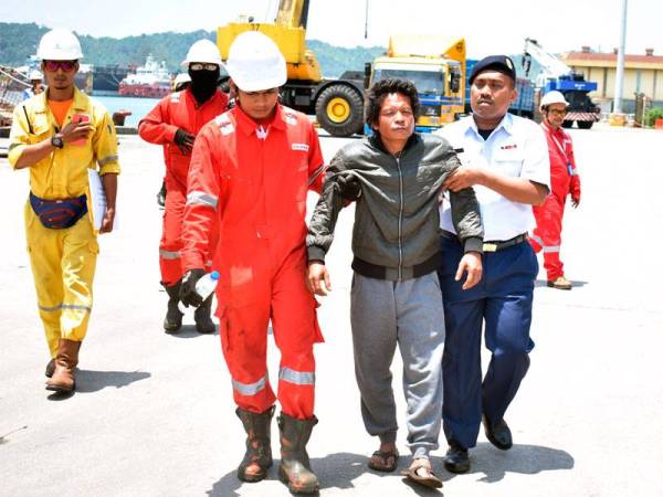 Nelayan Thailand yang diselamatkan dipapah semasa tiba di Pelabuhan Kemaman, tengahari semalam.