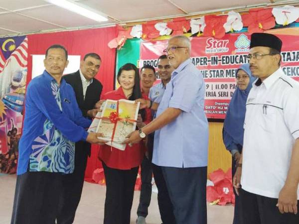 Mahfuz (tiga dari kanan) menyerahkan akhbar kepada Pengetua SMK Jabi, Shafin Mohd Daud (kiri) selepas merasmikan Program NiE tajaan Perkeso dengan kerjasama Star Media Group di SMK Jabi di sini tadi.