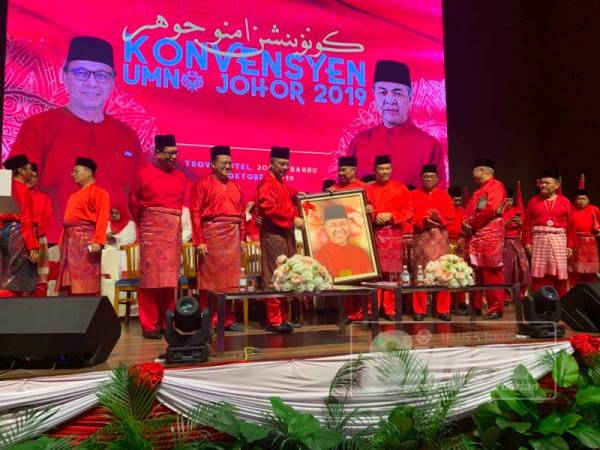 Hasni (tiga dari kiri) menyampaikan potret Ahmad Zahid sebagai gimik perasmian Majlis Konvensyen UMNO Johor 2019 di sini hari ini.