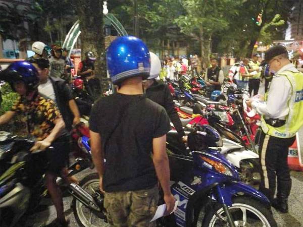 Anggota polis memeriksa penunggang motosikal pada Op Bersepadu di Jalan Raja Laut, Kuala Lumpur di sini awal pagi tadi.