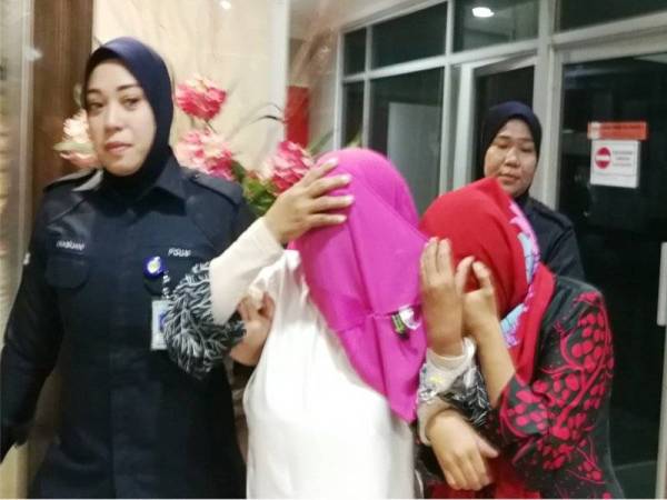 Kedua-dua tertuduh sewaktu diiringi polis di Mahkamah Majistret Kuala Terengganu, hari ini.