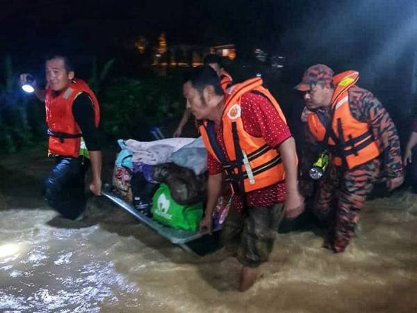 Anggota bomba membantu memindahkan barangan peribadi penduduk ke pusat pemindahan.