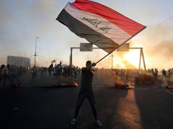 Seorang penunjuk perasaan mengibarkan bendera Iraq ketika tunjuk perasaan membantah masalah rasuah dan pengangguran di Baghdad pada 5 Oktober lalu.- Foto: AFP