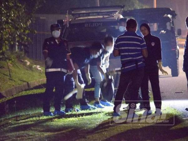 Anggota forensik mengangkat beg plastik berisi keretan mayat di Kampung Ladang, Krubong, Melaka, semalam.