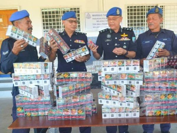 Norzaid (dua dari kanan) menunjukkan rokok putih pelbagai jenama yang berjaya dirampas Pasukan Polis Marin (PPM) Wilayah Tiga Tok Bali.