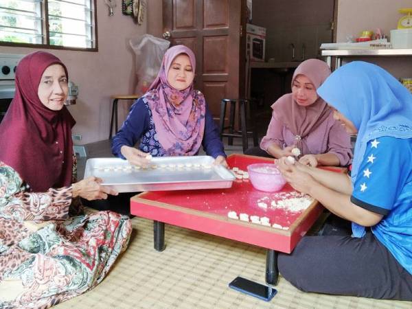 Induk Chichuk (kiri) menunjukkan biskut bangkit keju yang diusahakan di Kampung Serkat Tanjung Piai.