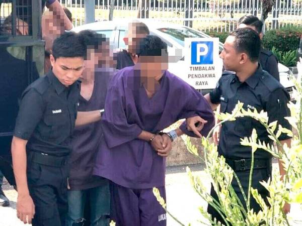 Suspek kes pembunuhan tragis diiringi polis ketika tiba di pekarangan Kompleks Mahkamah Melaka, Ayer Keroh di sini hari ini.