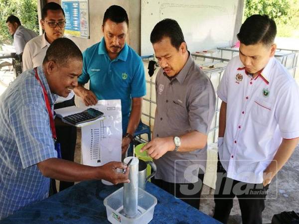 Azman (dua dari kanan) melihat cara-cara pengumpulan lateks di Depo Pengumpulan Skrap Kampung Selamat hari ini.