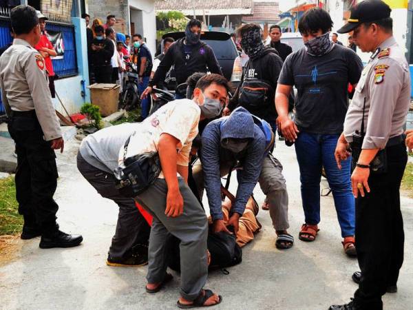 Polis memberkas suspek militan di luar sebuah rumah di Bekas, Jawa Barat pada akhir minggu lalu. - Foto AFP