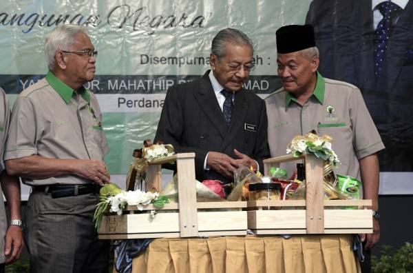 Dr Mahathir memperkatakan sesuatu kepada Presiden PKPKM Datuk Aliasak Ambia (kiri) dan Pemangku Timbalan Presiden PKPKM, Meor Harun Meor Osman( kanan) ketika merasmikan Mesyuarat Agung Dwitahunan ke-22 Persatuan Kebangsaan Pekebun-Pekebun Kecil Malaysia di sebuah hotel hari ini. -Foto Bernama