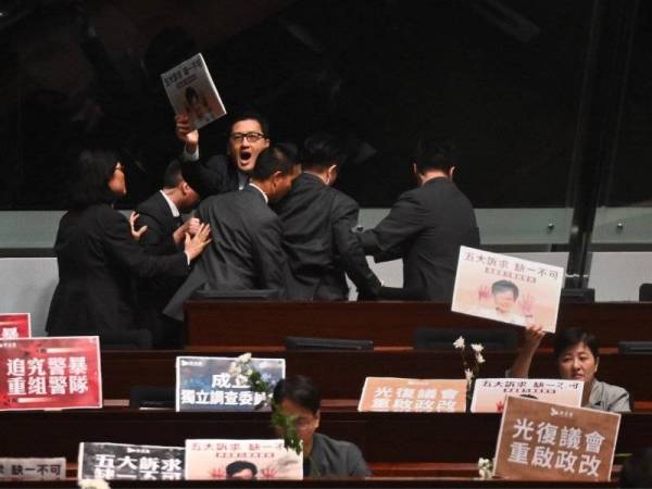 Ahli Parlimen prodemokrasi, Lam Cheuk-ting (tengah) dihalang anggota keselamatan ketika beliau mula melaungkan slogan mengkritik Lam. - Foto: AFP