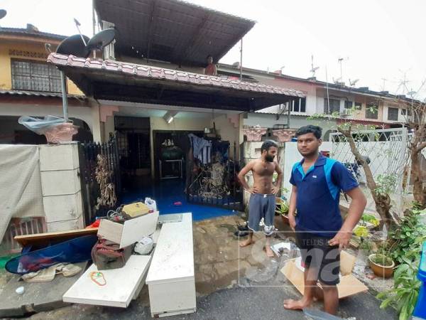 Penduduk sedang membersihkan rumah akibat banjir kilat yang melanda di Taman Sri Muda di sini petang semalam.