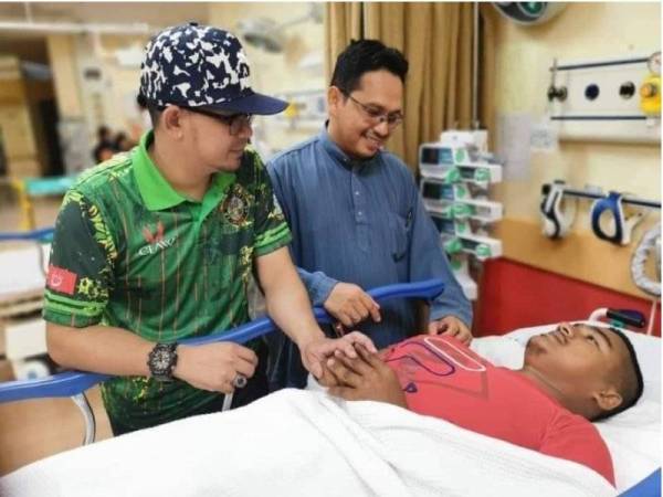 Amran (kanan) melawat salah seorang pesakit di Hospital Gua Musang.