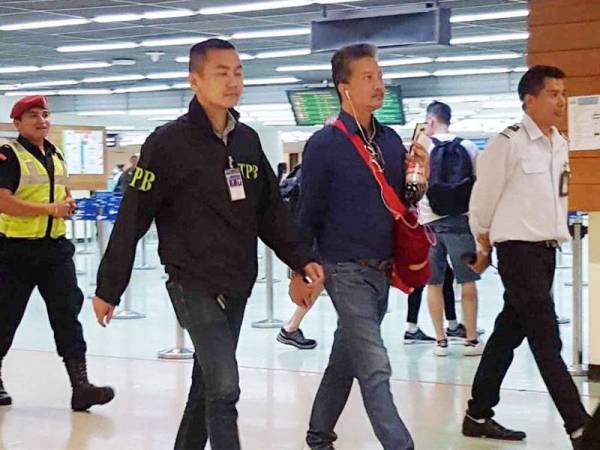 Thananat Siripiyaporn (tiga dari kiri) yang menyamar sebagai jutawan ditahan di Don Mueang sebaik tiba dari Hong Kong.