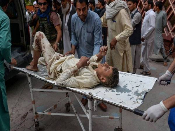 Sukarelawan membantu seorang mangsa cedera susulan letupan bom di sebuah masjid di daerah Haska Mina, Afghanistan semalam. - Foto AFP