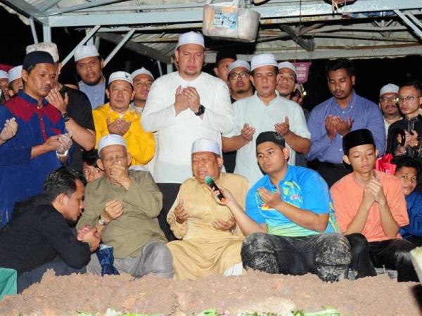 Miswan Sayuti (dua, kiri, duduk) mengaminkan doa ketika bacaan talkin pada pengkebumian anaknya Allahyarham Azalan Miswan 50, yang merupakan kakitangan Perbadanan Kemajuan Negeri Selangor (PKNS) yang maut dalam kemalangan di Turki selepas pengkebumian di Tanah Perkuburan Islam Seksyen 21 Shah Alam. -Foto Bernama