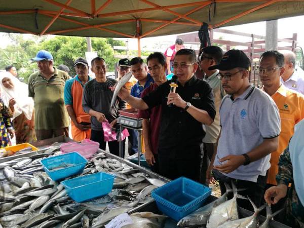 Salahuddin membantu peniaga membuat lelongan ikan yang dijual pada harga jauh lebih rendah daripada harga pasaran kepada pengunjung selepas melancarkan Program BPR di Serkat semalam.