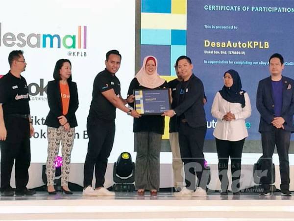 Rina (empat dari kiri) menyaksikan penyerahan dokumen MoU antara ELokal Sdn Bhd dan Lazada di tapak Karnival Usahawan Desa di Putrajaya hari ini.