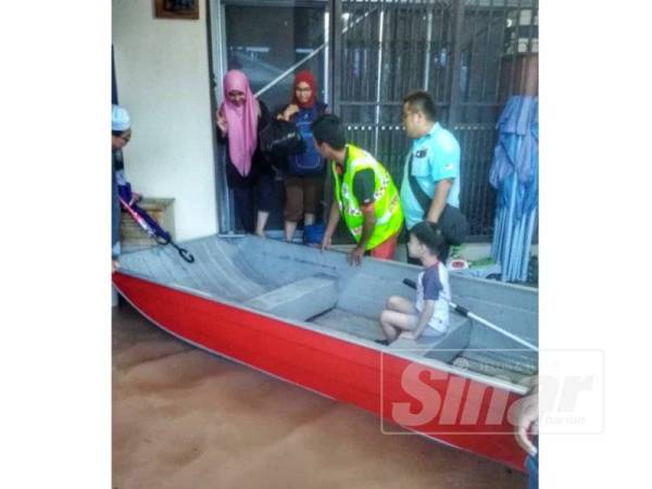 Anggota Pasukan Bomba Sukarela membantu memindahkan mangsa banjir dari rumah mereka ke PPS yang dibuka.