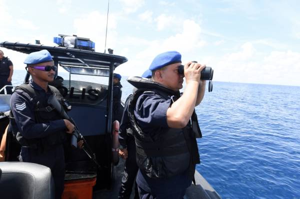 Mohamad Pajeri Ali (kanan) menggunakan teropong ketika menyertai operasi mencari dan menyelamat (SAR) beberapa individu yang masih dikhuatiri lemas di perairan Merabung, Tungku, dekat sini, tiga hari lalu. -Foto Bernama