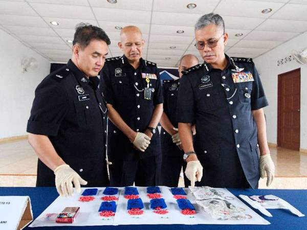 Hasanuddin (kanan) menunjukkan rampasan pil yaba di Kampung Batu Melintang pada sidang media di IPD Jeli hari ini. - Foto Shahuri Awang