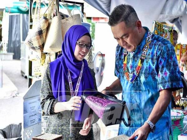 IBRAHIM (kanan) singgah di salah sebuah gerai jualan di Festival Kraf Borneo di Waterfront Kuching, Sarawak semalam.