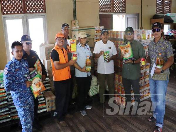 Zulkhairi (empat dari kanan) dan Mohd Zakaria (tiga dari kanan) mengagihkan barangan makanan kepada wakil penduduk untuk beberapa pangkalan hadapan di Pulau Tioman.