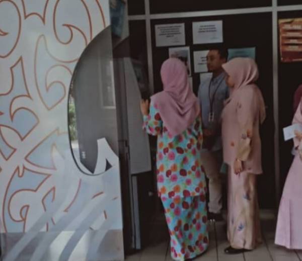 Tertuduh, Nik Hanna Yasmin Nik Muhammad, 36, (kanan) sedang membuat urusan membayar denda RM8,000 yang dijatuhkan kepadanya oleh Mahkamah Sesyen di sini hari ini di mesin pembayaran di pekarangan bangunan Kompleks Mahkamah Terengganu.