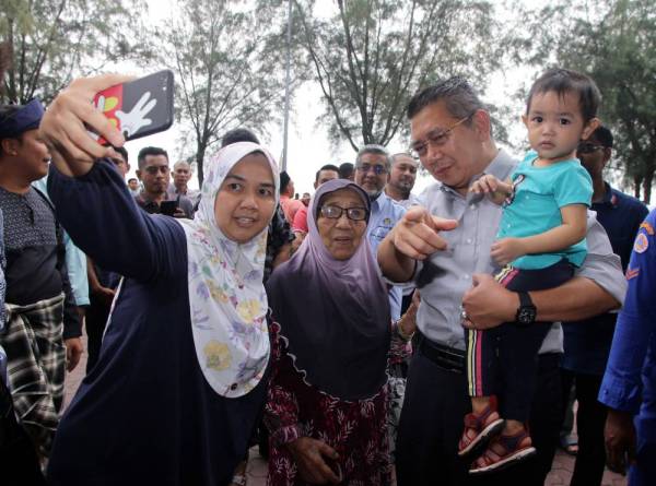 Salahuddin (kanan) berswafoto bersama orang ramai ketika hadir untuk merasmikan Program Makan Perpaduan "Makanan Menyatukan Kita" di Pusat Perdagangan, Bandar Baru Pontian, hari ini. - Foto: Bernama
