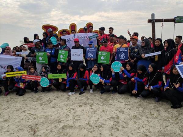 Peserta bergambar di hadapan papan tanda Pantai Balok sebelum memulakan acara mengutip sampah sempena program Sayangi Pantai Kita di Pusat Rekreasi Balok di sini hari ini.